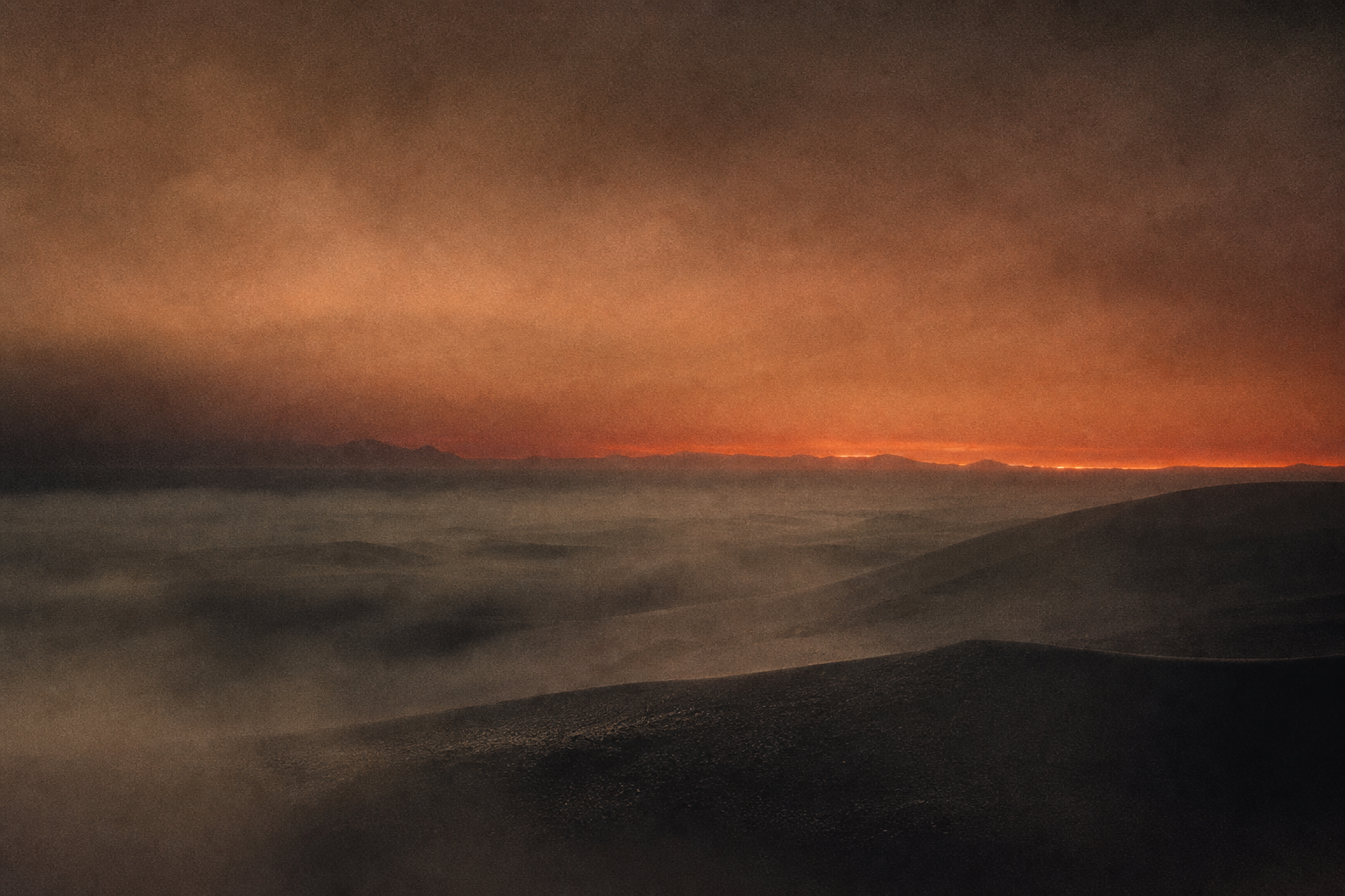 Cropped frame of pale mist over dark dunes.